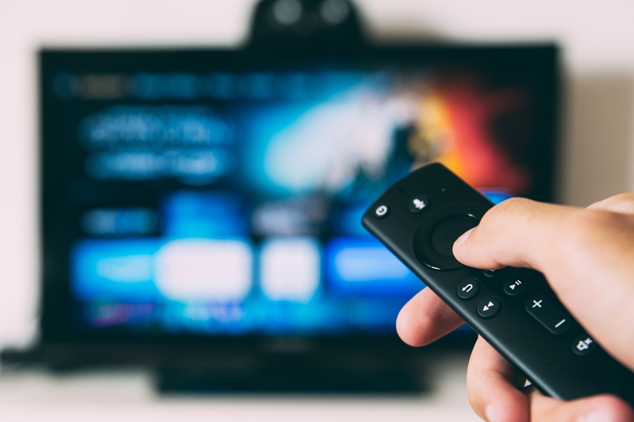 Hand pointing a Fire TV remote at a TV