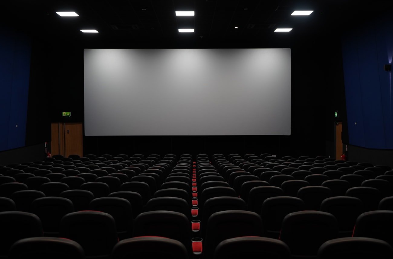 Empty cinema with red seats facing a big screen